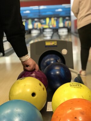 Abends in der Bowlinghalle. Bowlingkugeln und eine Hand